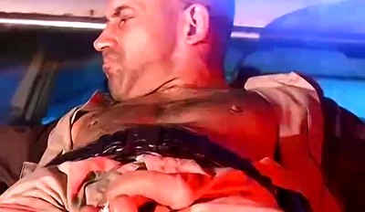 Officer Derek da Silva bound to the hood of a car